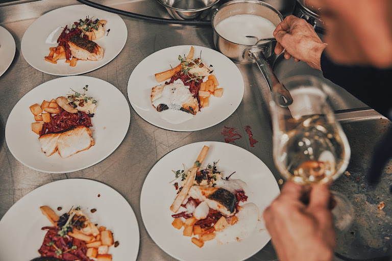 Sechs professionell angerichtete Fischteller auf der Edelstahlarbeitsplatte, bereit zum Servieren