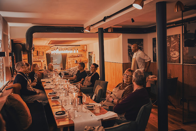 Kochkursgruppe sitzt am langen Restauranttisch zum gemeinsamen Abendessen mit Rainer Trautenbach