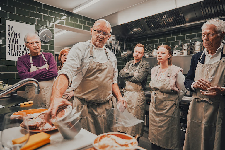 Rainer Trautenbach demonstriert die Zubereitung vor einer Gruppe aufmerksamer Kochkursteilnehmer
