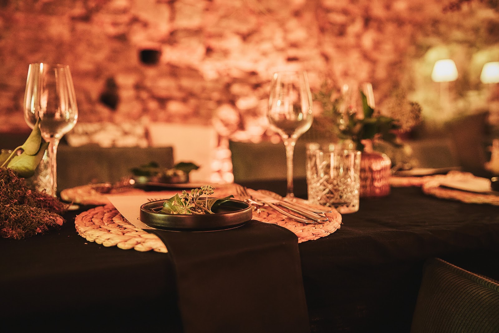 Nahaufnahme des festlich gedeckten Tisches im Gewölbekeller – Kristallgläser, Besteck und Kerzen