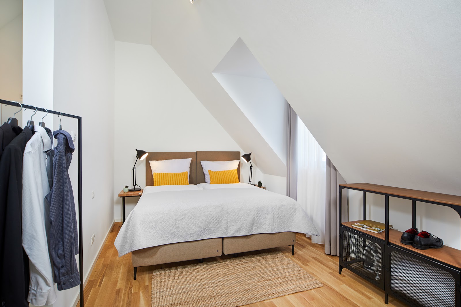 Helles Schlafzimmer mit Doppelbett, gelben Kissen und Dachschräge in der Ferienwohnung Weinforum Franken Eibelstadt