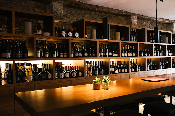 Weinregal mit beleuchteten Holzfächern und Verkostungstisch in der Vinothek Weinforum Franken